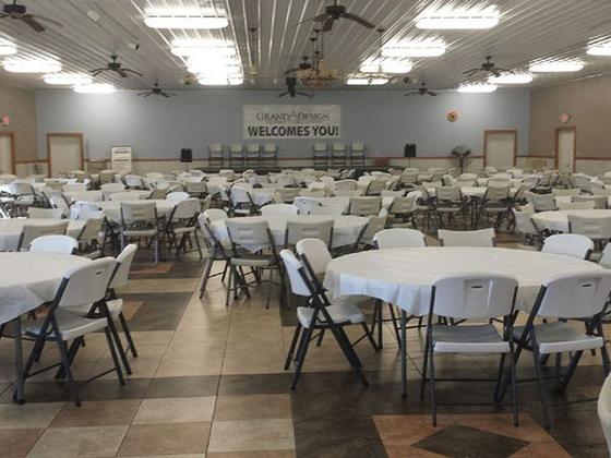 Large banquet hall with round tables and white folding chairs, and a welcome banner on the far wall