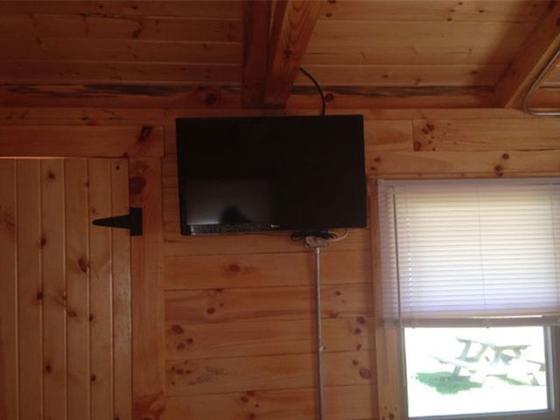 Flat-screen TV mounted on a pine wall beside a window