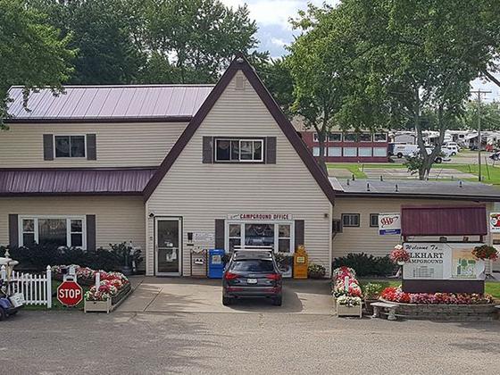 Campground office with a white picket fence, flower beds, and a playground beside it